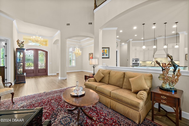 living room featuring light hardwood / wood-style flooring, a notable chandelier, a healthy amount of sunlight, and crown molding