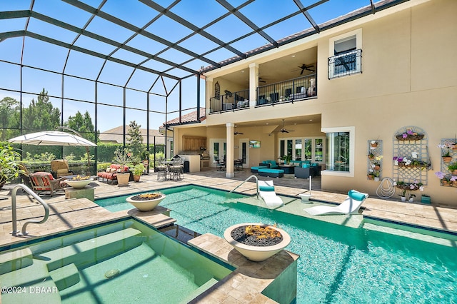 view of swimming pool featuring a hot tub, an outdoor living space with a fire pit, a patio, a lanai, and ceiling fan