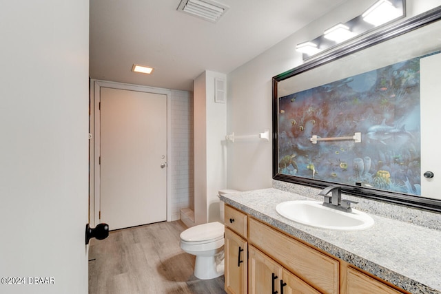 bathroom featuring toilet, vanity, hardwood / wood-style floors, and walk in shower