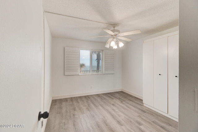 unfurnished bedroom with light hardwood / wood-style floors, ceiling fan, a textured ceiling, and a closet