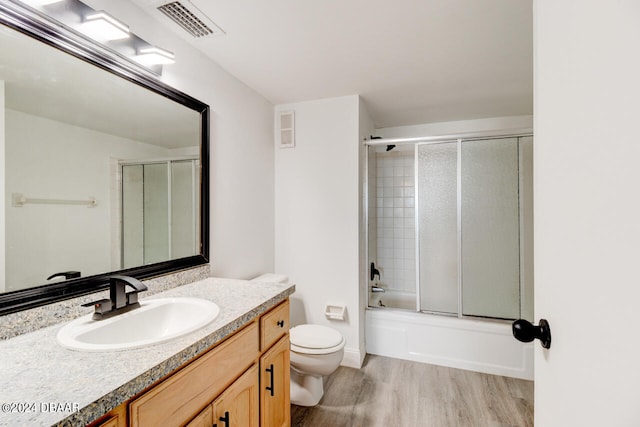 full bathroom with hardwood / wood-style floors, enclosed tub / shower combo, toilet, and vanity