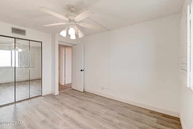 unfurnished bedroom featuring ceiling fan, a closet, and light hardwood / wood-style flooring