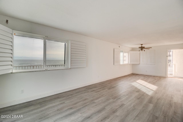 spare room with light hardwood / wood-style floors, ceiling fan, and a water view