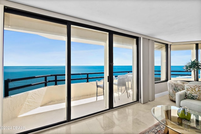 interior space featuring light tile patterned floors, a beach view, and a water view