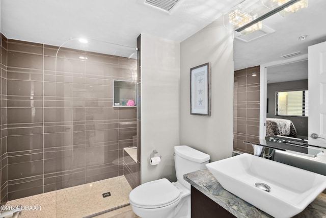 bathroom with toilet, vanity, and a tile shower