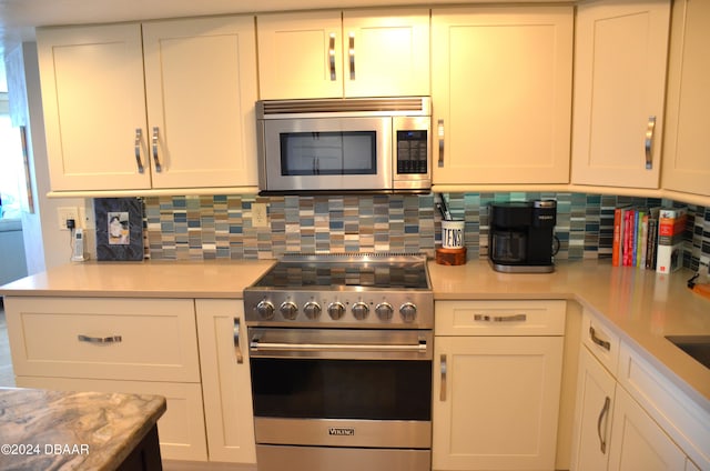 kitchen with tasteful backsplash, white cabinetry, and appliances with stainless steel finishes