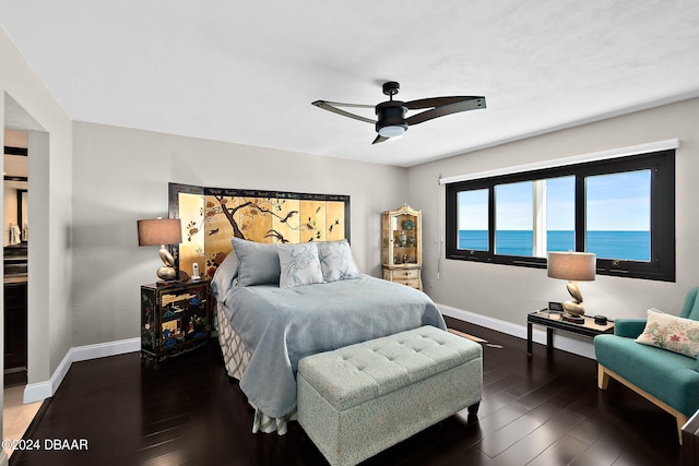 bedroom with a water view, dark hardwood / wood-style floors, and ceiling fan