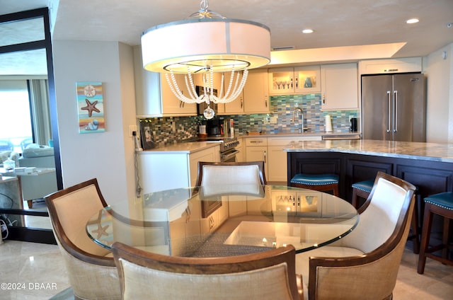 interior space featuring sink, light stone counters, tasteful backsplash, hanging light fixtures, and high quality appliances