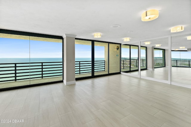 empty room featuring expansive windows and a water view