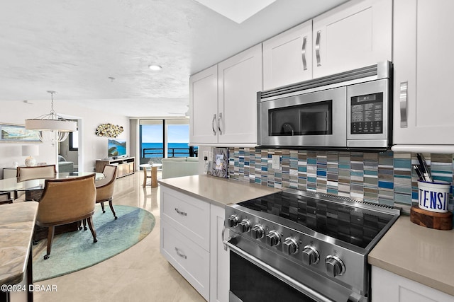 kitchen with stainless steel appliances, white cabinetry, tasteful backsplash, light tile patterned floors, and hanging light fixtures