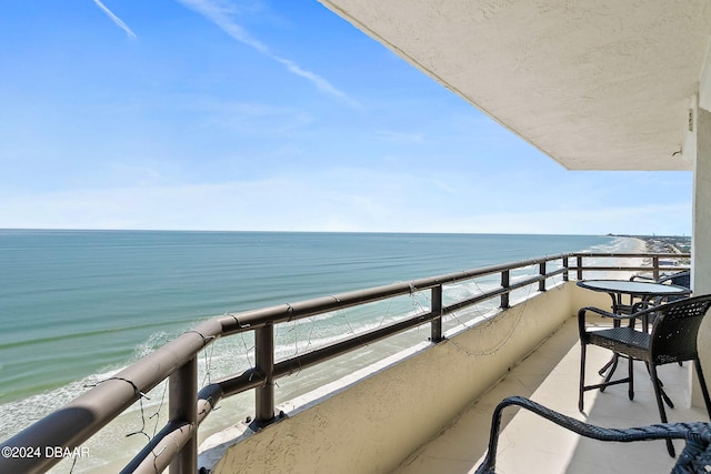 balcony with a water view and a view of the beach