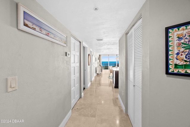 hallway featuring floor to ceiling windows and light tile patterned floors