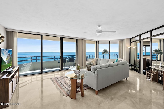 living room featuring ceiling fan, a water view, and floor to ceiling windows