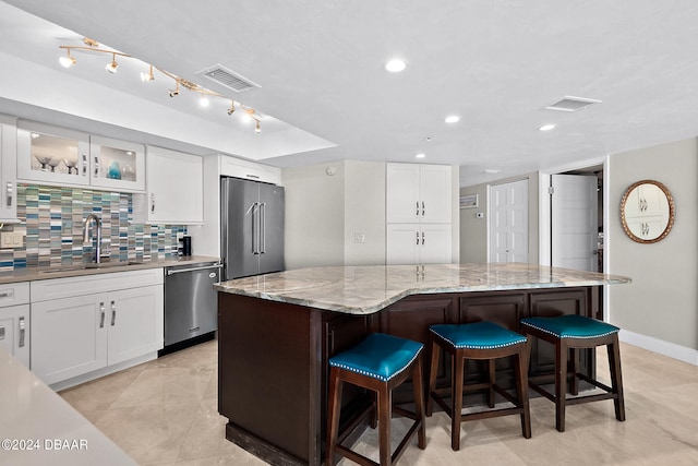 kitchen with white cabinets, appliances with stainless steel finishes, sink, and a center island