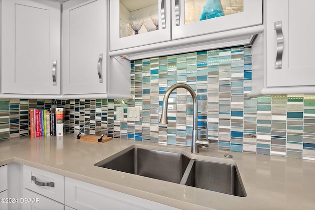 kitchen featuring white cabinetry, sink, and tasteful backsplash