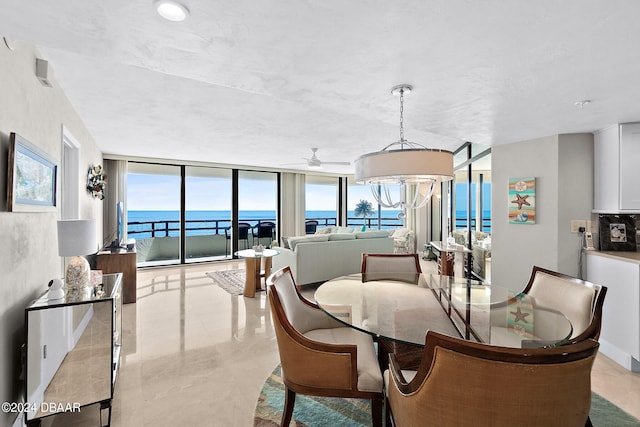 dining area with ceiling fan with notable chandelier, a wealth of natural light, a water view, and floor to ceiling windows