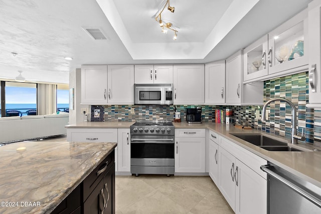 kitchen featuring stainless steel appliances, white cabinetry, sink, and backsplash