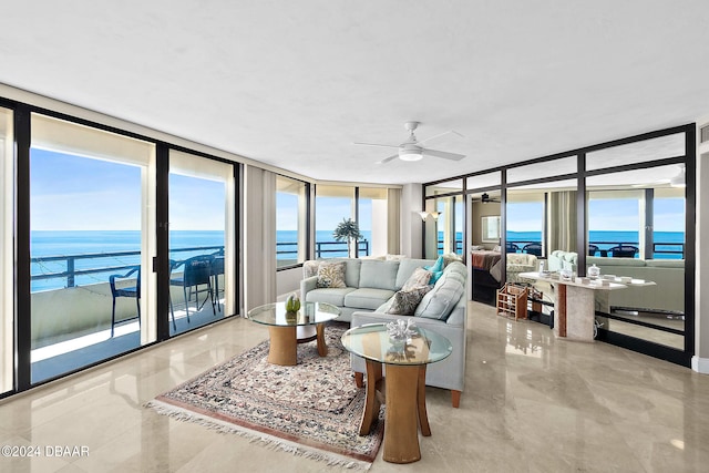 living room with a wealth of natural light, a water view, and ceiling fan