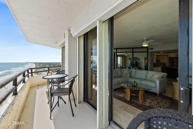 balcony featuring ceiling fan, outdoor lounge area, a view of the beach, and a water view