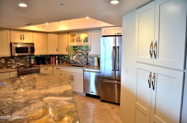 kitchen featuring premium appliances, decorative backsplash, white cabinetry, and sink