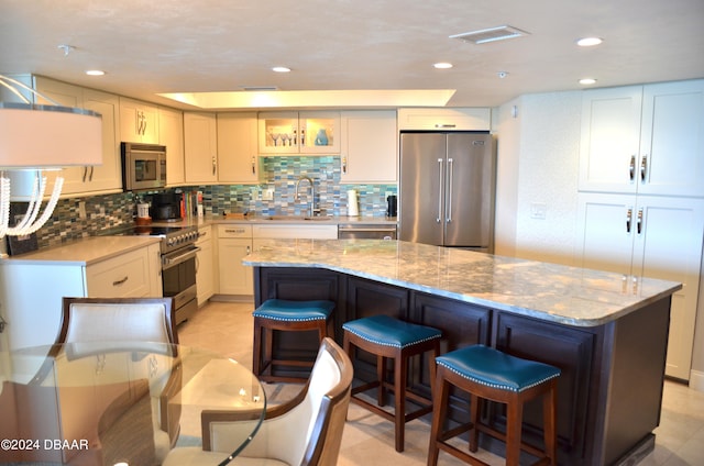 kitchen with white cabinets, a kitchen breakfast bar, high quality appliances, and a kitchen island