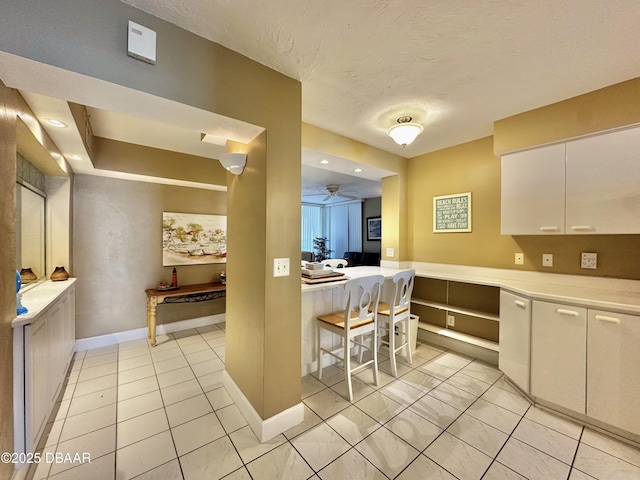 kitchen featuring light countertops, white cabinetry, baseboards, and a textured ceiling