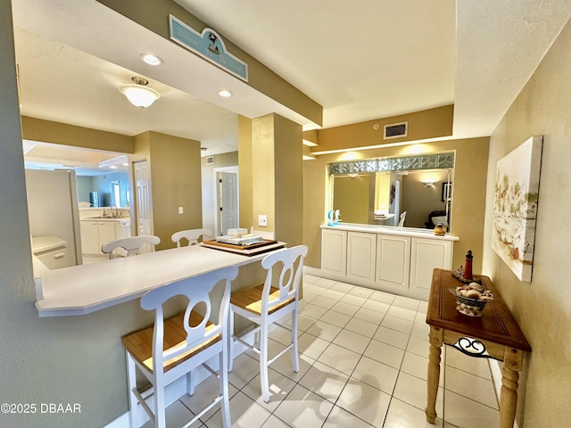 kitchen featuring light tile patterned floors, a breakfast bar, a sink, and a peninsula
