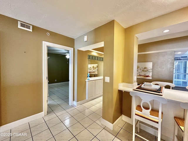 kitchen featuring a ceiling fan, baseboards, light tile patterned floors, light countertops, and a breakfast bar