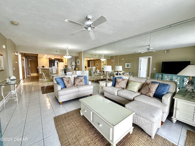 living room featuring a ceiling fan, light tile patterned flooring, baseboards, and a textured ceiling