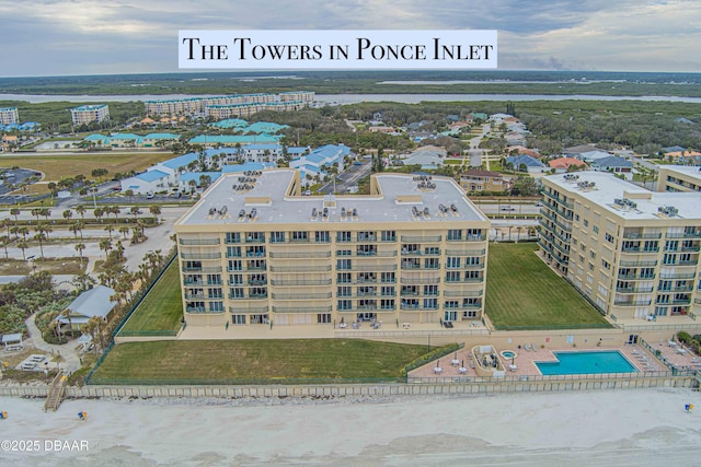 drone / aerial view of a pool area, apartment complex, and a large body of water