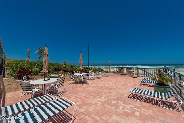 view of patio featuring view of water and beach and outdoor dining space