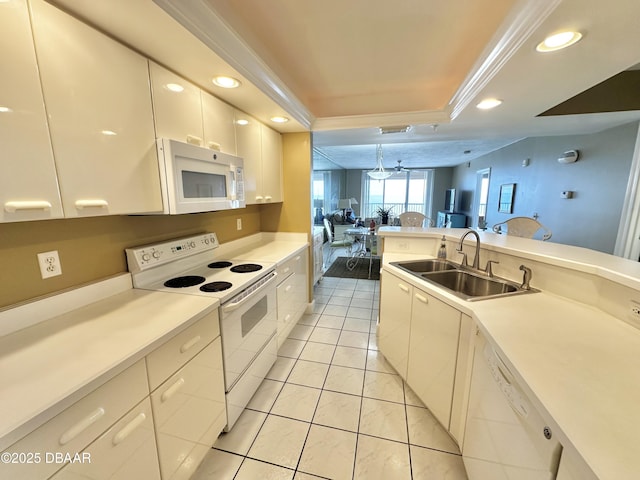 kitchen with white appliances, a sink, a raised ceiling, recessed lighting, and light countertops