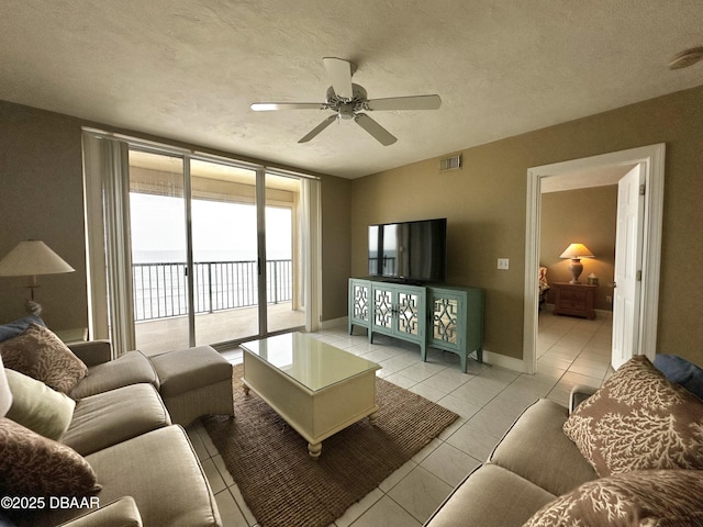 living room with ceiling fan, light tile patterned floors, and a textured ceiling
