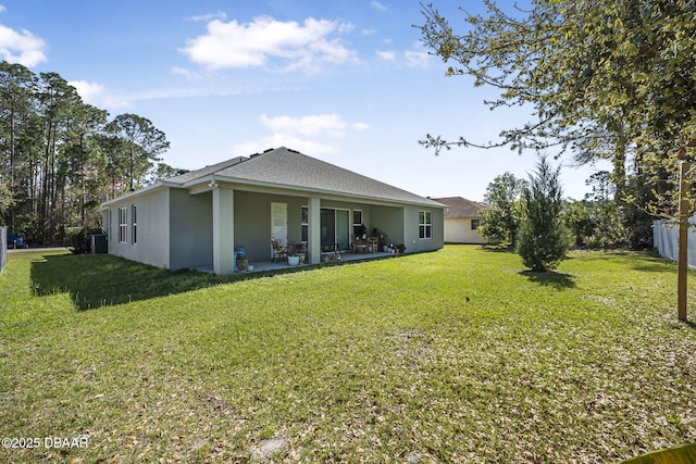 rear view of property featuring a patio area, fence, a lawn, and stucco siding