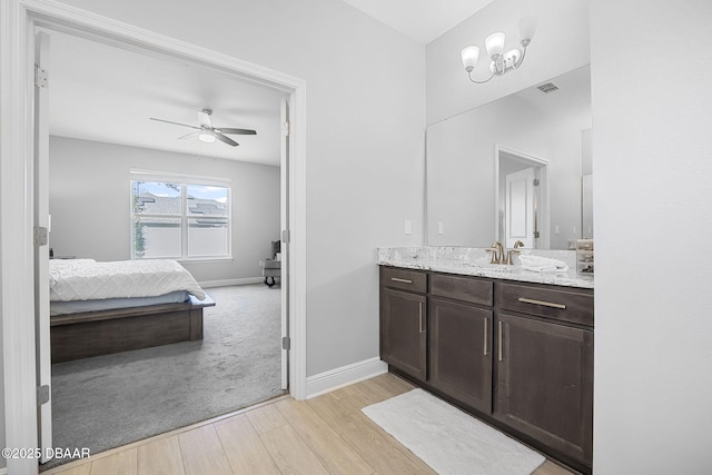 bathroom featuring baseboards, wood finished floors, ensuite bathroom, vanity, and ceiling fan with notable chandelier