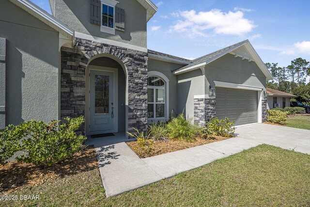 property entrance featuring stone siding, concrete driveway, an attached garage, and stucco siding