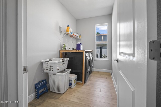 laundry area with baseboards, laundry area, light wood-style floors, and washer and dryer