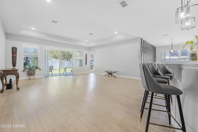 interior space with light wood-style floors, visible vents, and a raised ceiling