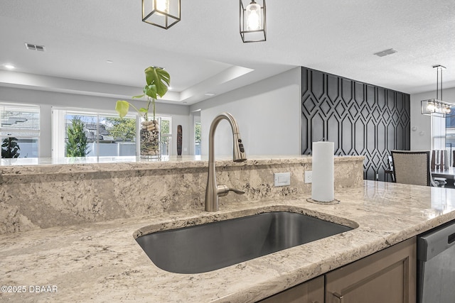 kitchen featuring dishwasher, hanging light fixtures, light stone counters, and a sink