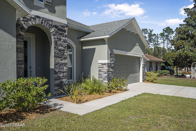 view of home's exterior featuring an attached garage, stone siding, driveway, a lawn, and stucco siding