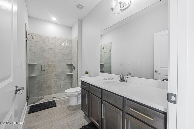 full bathroom featuring visible vents, a shower stall, toilet, and vanity