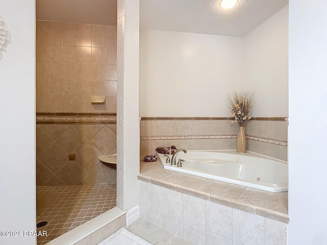 bathroom featuring a textured ceiling and shower with separate bathtub