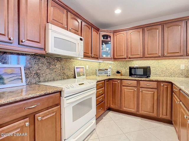 kitchen with light stone counters, light tile patterned floors, white appliances, and backsplash