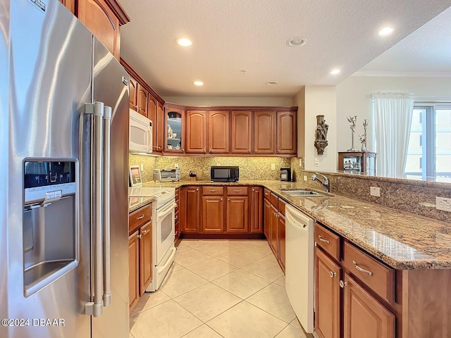 kitchen featuring light stone counters, decorative backsplash, sink, ornamental molding, and white appliances