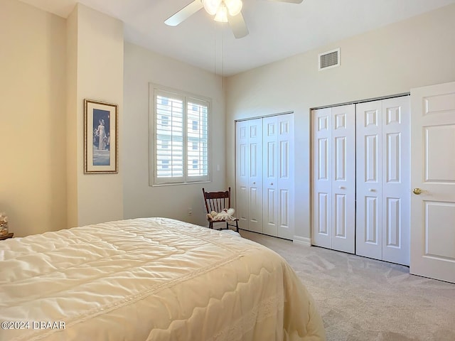 carpeted bedroom featuring ceiling fan and multiple closets