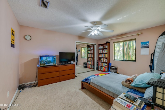 carpeted bedroom featuring ceiling fan and a textured ceiling