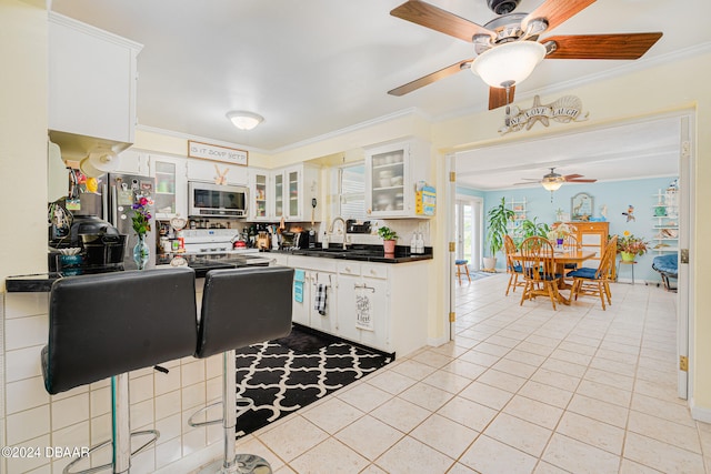 kitchen with tasteful backsplash, light tile patterned flooring, stainless steel appliances, crown molding, and white cabinets