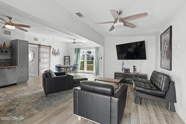 living room with a barn door and ceiling fan