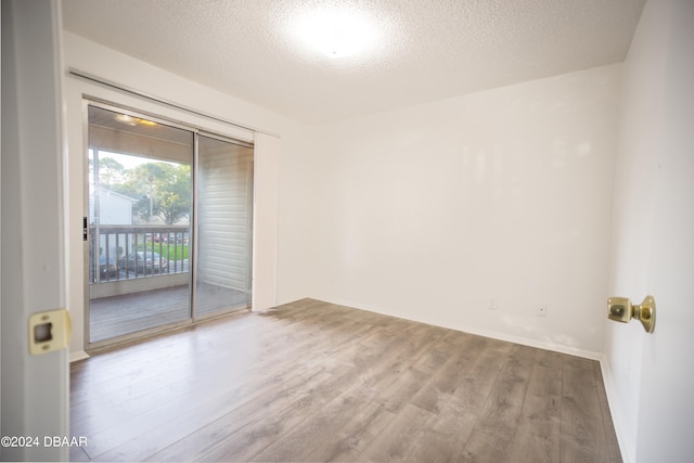 spare room with light wood-type flooring and a textured ceiling