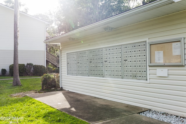 view of side of home featuring a mail area and a lawn